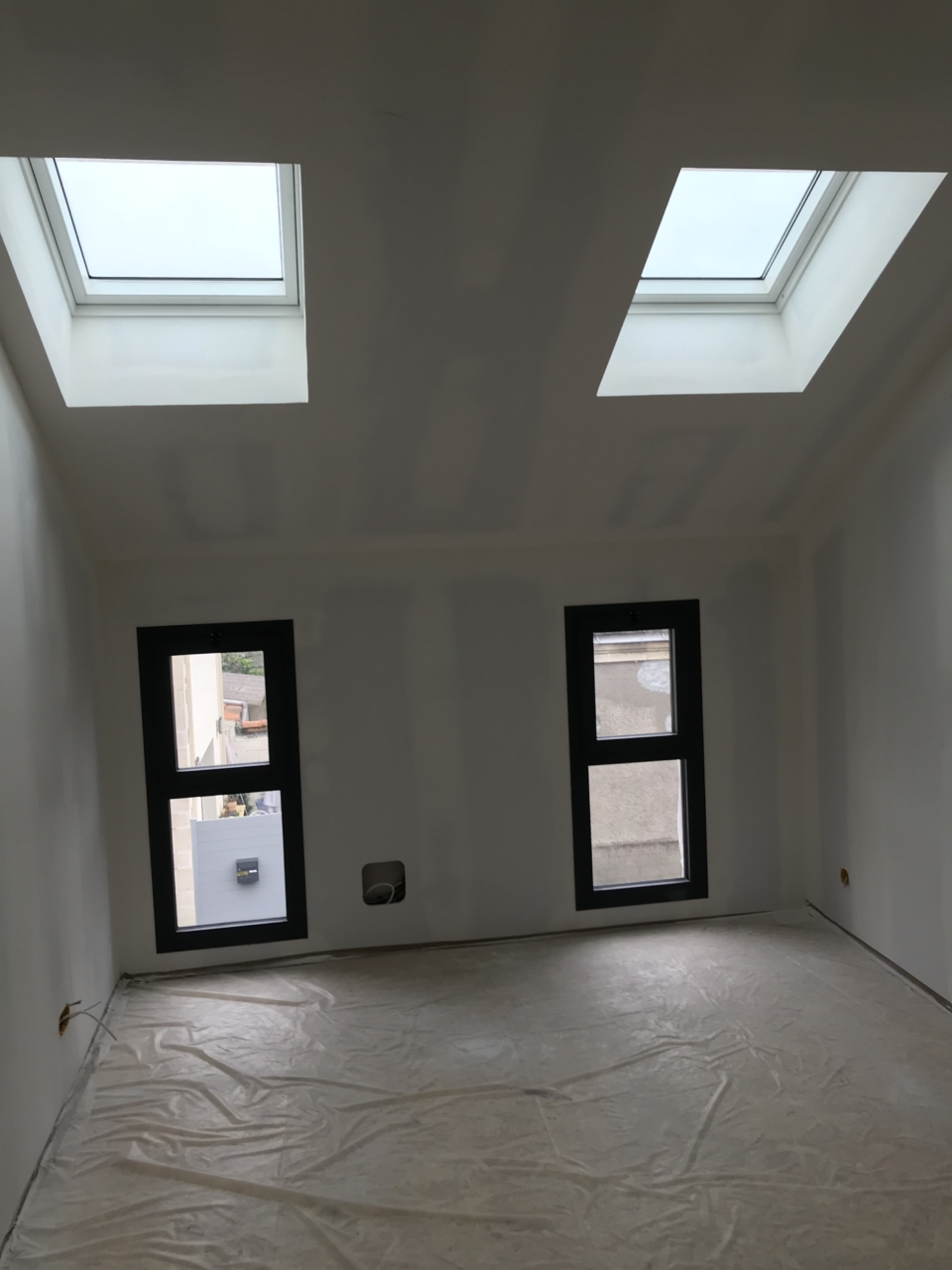 intérieur de la surélévation à Bordeaux en cours de travaux, avec deux fenêtre verticales RAL 7016
